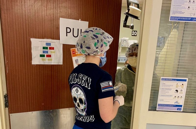 Tak proste zadanie, jak pozostanie lub opuszczenie pokoju pacjenta, jest bardziej skomplikowane na oddziale ratunkowym szpitala Mount Sinai ze względu na konieczność noszenia odzieży ochronnej, aby zapobiec rozprzestrzenianiu się COVID-19. Tutaj przez otwarte drzwi przechodzą środki medyczne.