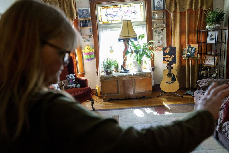 John McCarthys Foto und Gitarre werden gezeigt, als seine Frau Christine am ersten Ostern ohne ihn, Sonntag, den 4. April 2021, in ihrem Haus in Lincoln, RI, in ihrem Wohnzimmer steht Tag.