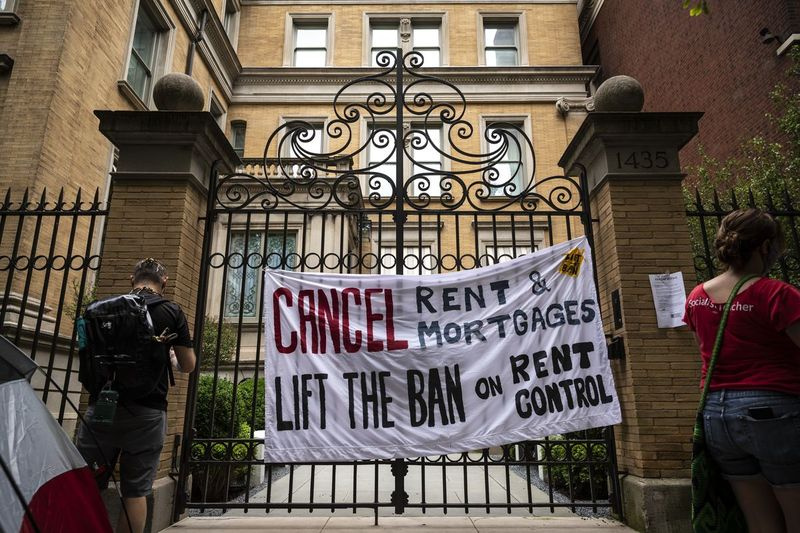 Protestatarii care cer guvernatorului J.B. Prtizker să ridice interdicția privind controlul chiriilor în Illinois în timpul pandemiei de coronavirus atârnă un semn și afișează anunțuri de evacuare pe conacul guvernatorului Gold Coast de pe strada North Astor, marți după-amiaza, 30 iunie 2020.