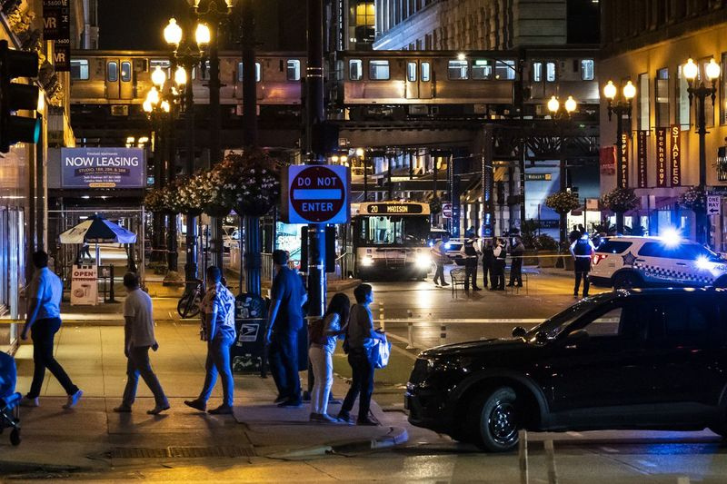 Przechodnie obserwują, jak policja Chicago prowadzi śledztwo w sobotę wieczorem w pierwszym bloku East Washington Avenue w Loop, gdzie kierowca autobusu CTA został fizycznie zaatakowany, a następnie zastrzelony.