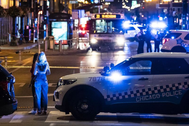 Przechodnie obserwują, jak policja Chicago prowadzi śledztwo w sobotę wieczorem w pierwszym bloku East Washington Avenue w Loop, gdzie kierowca autobusu CTA został fizycznie zaatakowany, a następnie zastrzelony.