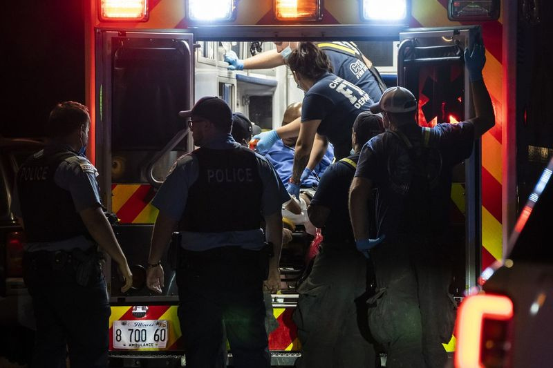 Ambulancefolk fra Chicagos brandvæsen behandler en mand, der blev skudt i benet tidligt mandag i baghaven til et hjem i 9900-blokken på South La Salle Street i Fernwood på South Side.