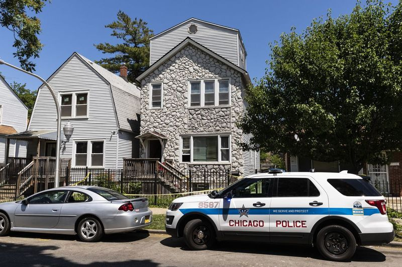 La policía de Chicago vigila y la cinta de la escena del crimen cuelga afuera de una casa en la cuadra 6200 de South Morgan, donde ocho personas fueron baleadas, cuatro fatalmente, dentro del edificio Englewood, el martes por la tarde, 15 de junio de 2021.