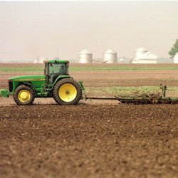 Obilný farmár obrába pole na pestovanie kukurice neďaleko Auburn, Illinois, v roku 1998.