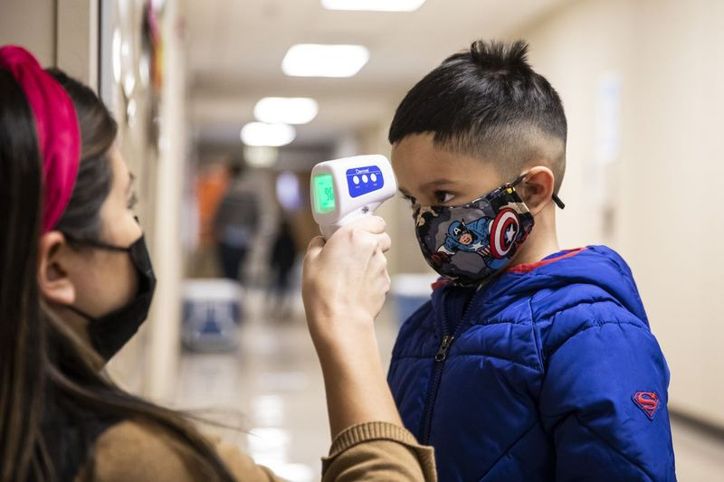 Um aluno da pré-escola verifica sua temperatura ao entrar na Dawes Elementary School, em Chicago.