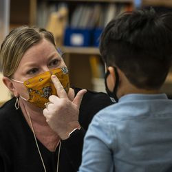 就学前の教師のアンジェラ・パヌーシュは、3810 W. 81stPlのDawesElementary Schoolでの授業中に、マスクを鼻にかぶせる方法を生徒に示しています。南西側、2021年1月11日月曜日の朝。