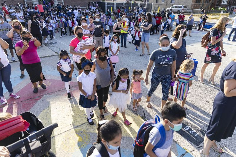 Esmaspäeval, 30. augustil 2021 ootavad õpilased ja lapsevanemad järjekorras, kuni õpilased kooli naasevad esimesel õppepäeval aadressil Alessandro Volta Elementary School 4950 N Avers Ave., Albany Park.