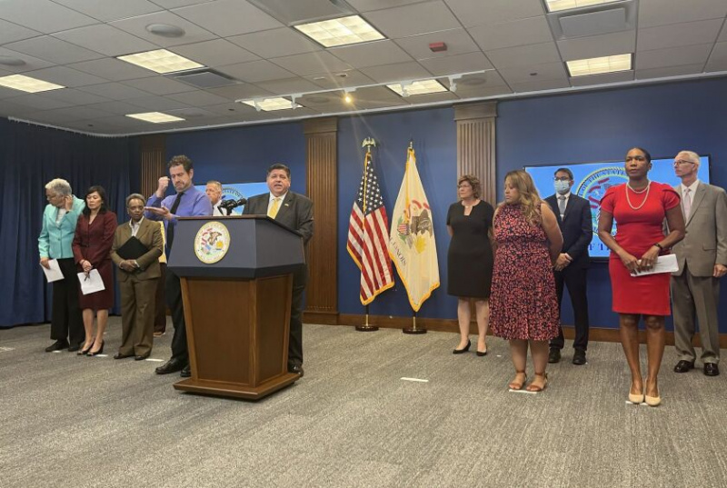   Una conferencia de prensa el miércoles en la que el gobernador J.B. Pritzker (en el atril) anunció una proclamación de desastre para ayudar al estado a ayudar a los inmigrantes transportados en autobús al estado desde Texas.