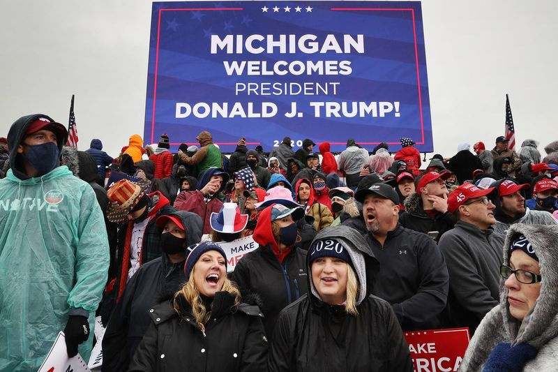 Tisíce příznivců čekají v chladném dešti na příjezd amerického prezidenta Donalda Trumpa během předvolebního shromáždění na mezinárodním letišti Capital Region International Airport 27. října 2020 v Lansingu v Michiganu.