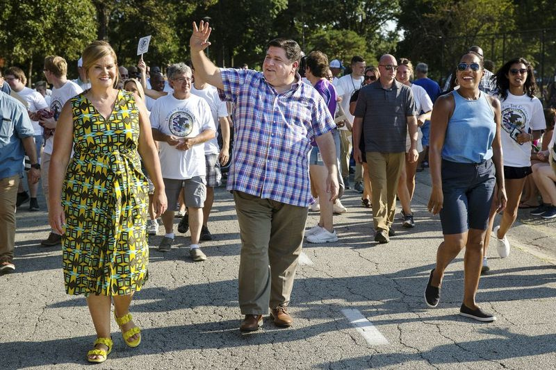 Guvernør J.B. Pritzker vinker, mens han går i Illinois State Fairs Twilight Parade i Springfield i 2019.