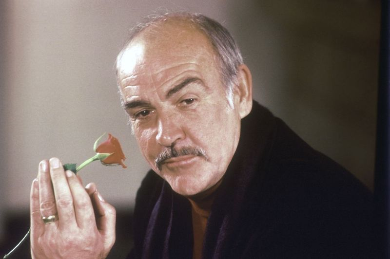 Aktieris Šons Konerijs 1987. gada preses konferencē Londonā tur rozi rokā, stāstot par savu jauno filmu Rozes vārds.