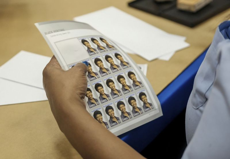 Een postbeambte houdt een boek vast met Gwen Ifill Black Heritage Commemorative Forever Stamps tijdens een postdienstceremonie in de Metropolitan African Methodist Episcopal Church, donderdag 30 januari 2020 in Washington.