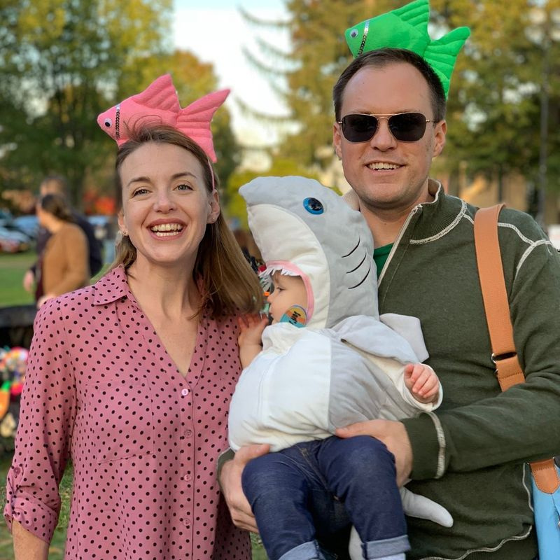 Jason e Jillian Simms e sua filha Fionnuala, em uma fantasia de tubarão em Town Green em Madison, Connecticut. Fionnuala ouviu pela primeira vez a canção Baby Shark quando ela tinha 8 meses de idade. Seus pais dizem que foi uma das primeiras coisas na vida que ela expressou diretamente