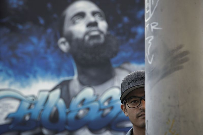 På detta foto den 17 april 2019 poserar väggmålningskonstnären Levi Ponce för foton framför en väggmålning som han tillägnat den dödade rapparen Nipsey Hussle i Los Angeles. | AP Photo/Jae C. Hong