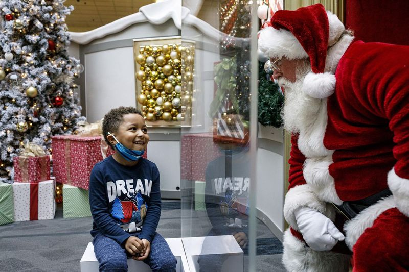 Kashden Dunlap îl vizitează pe Moș Crăciun, cu protocoale de siguranță în vigoare, la Capital City Mall din Lower Allen Township, Pennsylvania, la începutul acestei luni. Mall-urile fac tot posibilul pentru a-l proteja pe bătrânul vesel de coronavirus, inclusiv interzicerea copiilor să stea pe genunchi, schimbând complet cum arată o vizită a Moșului.