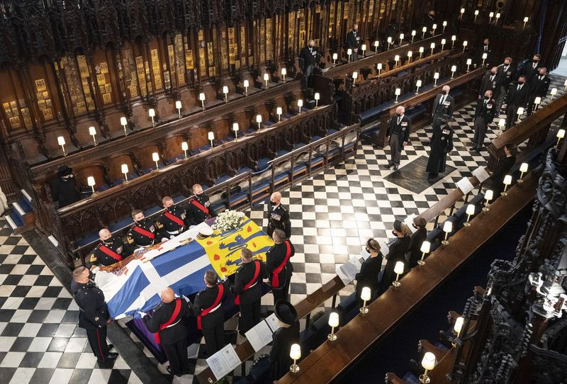 Regina Elisabeta urmărește cum purtătorii poartă sicriul ducelui de Edinburgh în timpul înmormântării sale, la Capela Sf. George din Castelul Windsor, Windsor, Anglia, sâmbătă, 17 aprilie 2021.