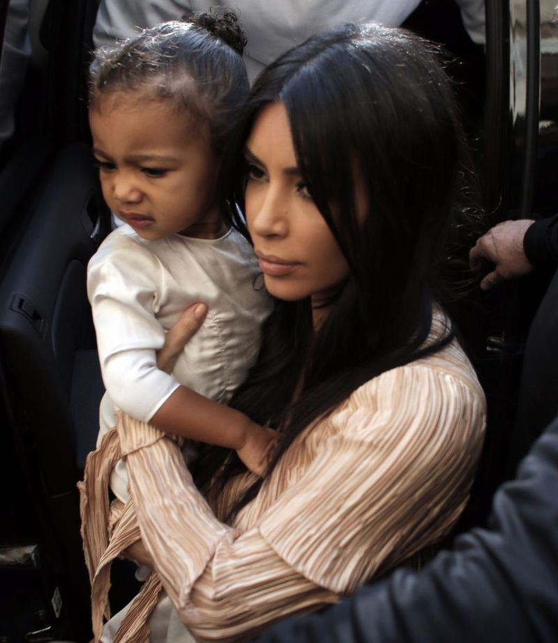 Kim Kardashian West nosi svojo hčer North West, ko ona in njen mož raper Kanye West (zadaj) izstopata iz avtomobila ob prihodu v armensko katedralo St. James v starem mestnem jedru Jeruzalema leta 2015.