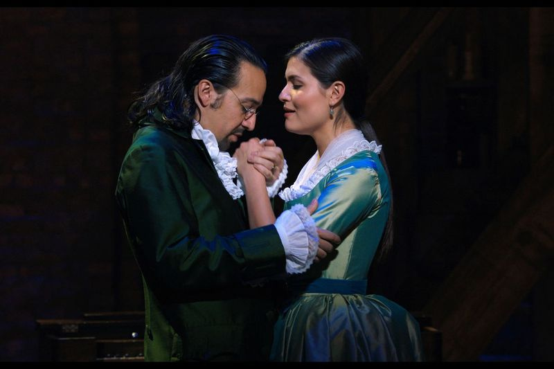Linas Manuelis Miranda įkūnija Aleksandrą Hamiltoną, o Phillipa Soo – Elizą Hamilton filmuotoje originalios Brodvėjaus Hamiltono produkcijos versijoje.