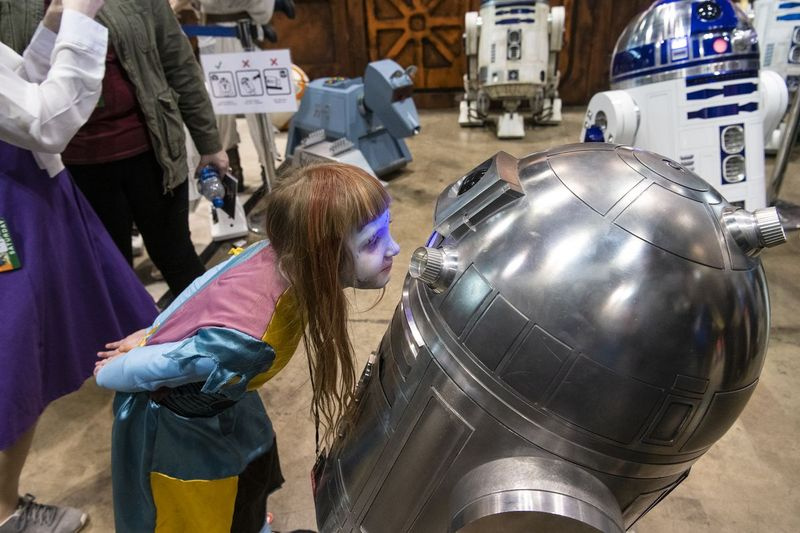 En ung pige ser på en R2D2-robot fra Star Wars lavet af Chi2-D2, Chicago-afdelingen af ​​International R2-D2 Builders Club, på C2E2, afholdt lørdag på McCormick Place.