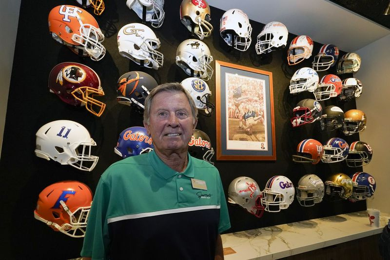 Steve Spurrier stojí pred výkladom prilieb tímov, za ktoré predtým hrával alebo trénoval vo svojej novej reštaurácii Gridiron Grill v Gainesville na Floride. Reštaurácia slúži aj ako Spurrierovo osobné múzeum.