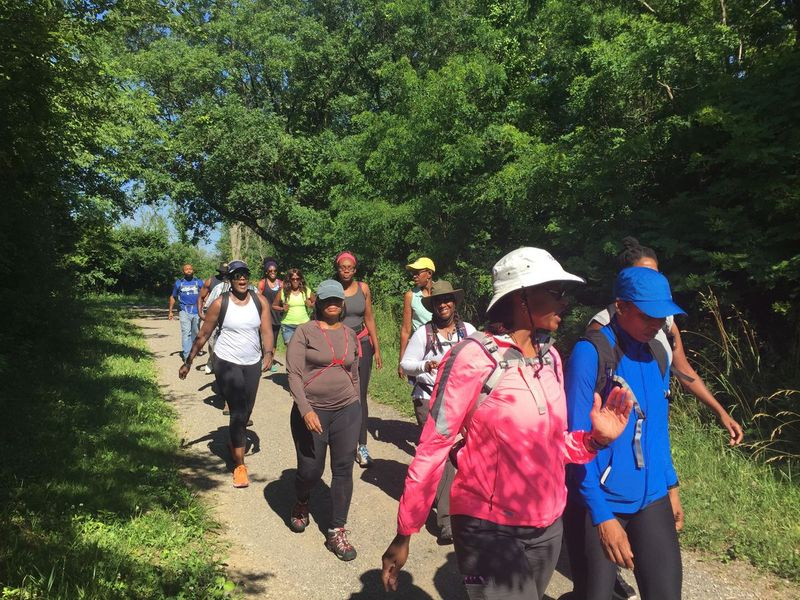 Persone che camminano con i cappelli lungo un sentiero con alberi intorno a loro