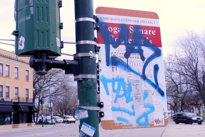 Un cartello stradale coperto di graffiti in Logan Square.