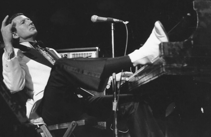   Jerry Lee Lewis apoya su pie en el piano mientras se recuesta y agradece los aplausos de los fanáticos durante el quinto Rock 'n' Roll Revival anual en el Madison Square Garden de Nueva York en 1975. | punto de acceso