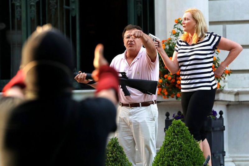 Nesta foto de arquivo de 28 de junho de 2020, os proprietários armados Mark e Patricia McCloskey, parados em frente a sua casa ao longo de Portland Place, enfrentam manifestantes marchando para a casa da prefeita de St. Louis, Lyda Krewson, no West End de St. Louis.