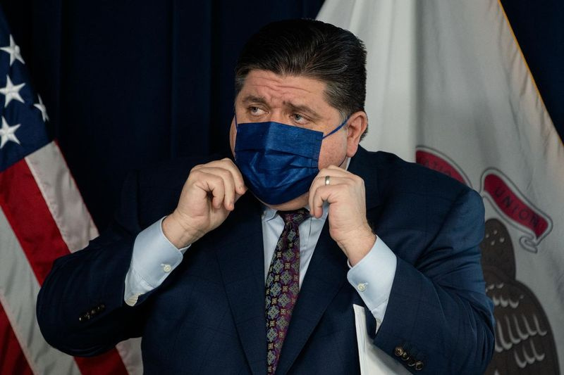 Gubernator J.B. Pritzker zakłada maskę podczas styczniowej konferencji prasowej w James R. Thompson Center.
