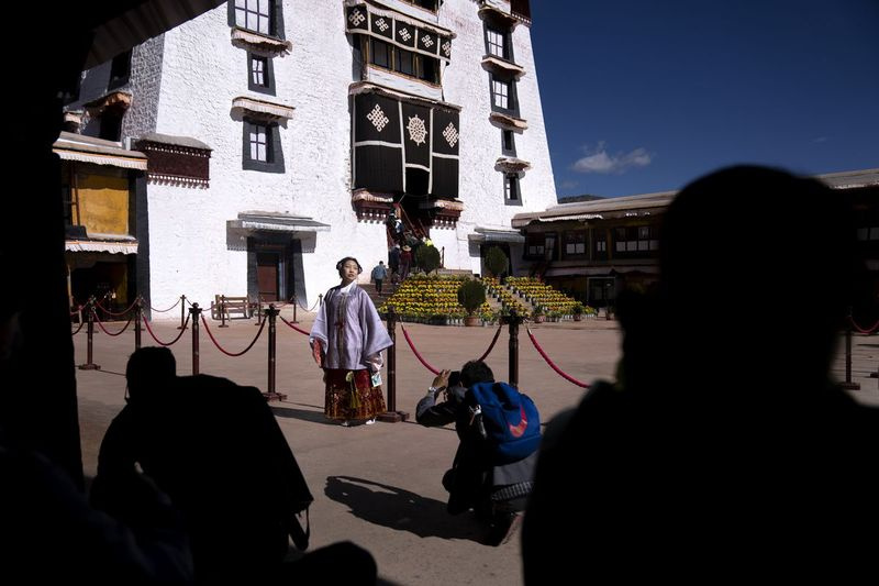 En kinesisk turist i tibetansk kjole poserer for et bilde på en gårdsplass ved Potala-palasset i Lhasa i den vestlige Kinas autonome region Tibet.