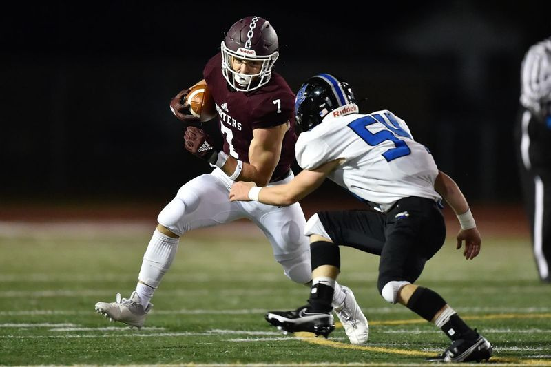 Ty Schultz (7) z Lockportu hrá loptu proti Charlesovi Nevingerovi (54) z Lincoln-Way East.