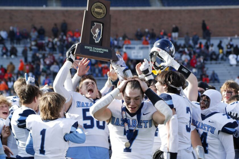  Zach Hayes (7) de Nazareth reage quando William Beargie (50) ergue o troféu estadual IHSA Classe 5A entre os companheiros de equipe após vencer o jogo contra Peoria.