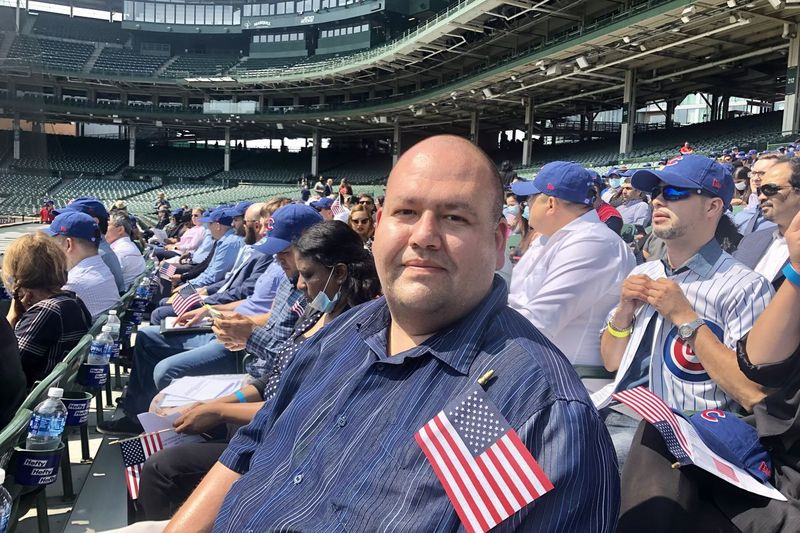 Hector Perez zit op de tribune bij de derde honklijn op Wrigley Field Friday. Hij was een van de 172 mensen die tijdens een speciale naturalisatieceremonie nieuwe burgers werden. Perez, 38, staat te popelen om familieleden in Mexico te zien bezoeken en maakt zich geen zorgen dat hij terug wordt gelaten in de Verenigde Staten.