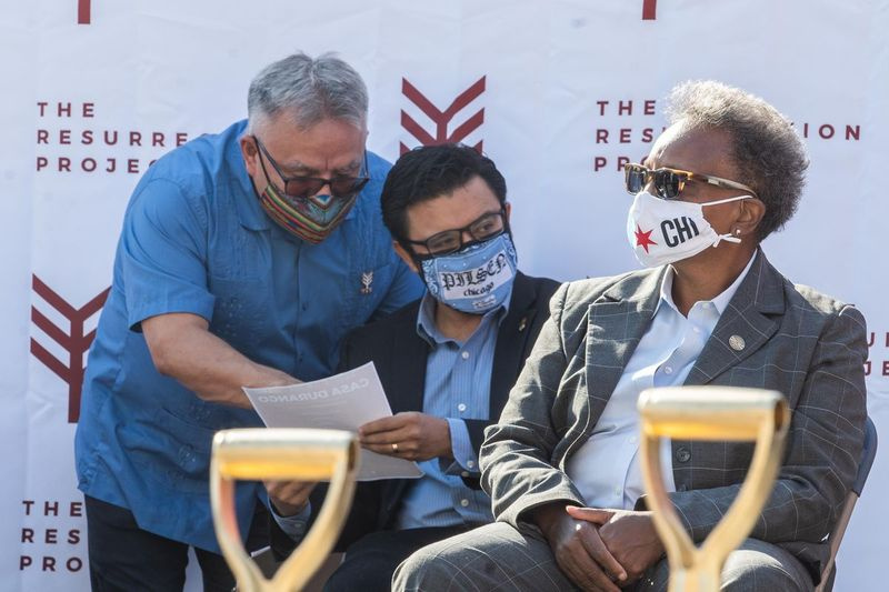Čikagos merė Lori Lightfoot sėdi scenoje, o Raulis Raymundo, Resurrection Project generalinis direktorius (kairėje), kalbasi su Aldu. Byronas Sigcho-Lopezas (25 m.) ketvirtadienį per prisikėlimo projekto „Casa Durango“, įperkamo būsto vystymo Pilzeno kaimynystėje, įkūrimo ceremonijoje.