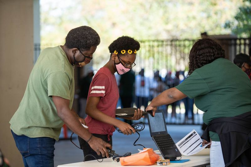 Charlie Cobbs, izquierda, y su hija Crystal, derecha, recogen la computadora portátil de Crystal en Morgan Park High School en Morgan Park el sábado por la mañana, 5 de septiembre de 2020. El personal distribuyó computadoras portátiles a los estudiantes antes del inicio de clases. | Pat Nabong / Sun-Times