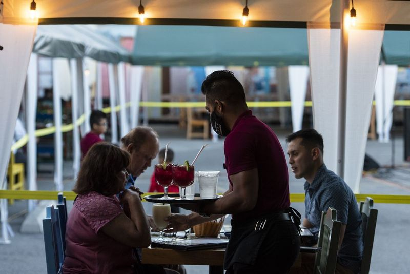 A principios de este mes, se sirven bebidas a una familia sentada en el patio al aire libre de Mi Tierra. Mi Tierra convirtió su estacionamiento en un comedor al aire libre debido a la pandemia de COVID-19.