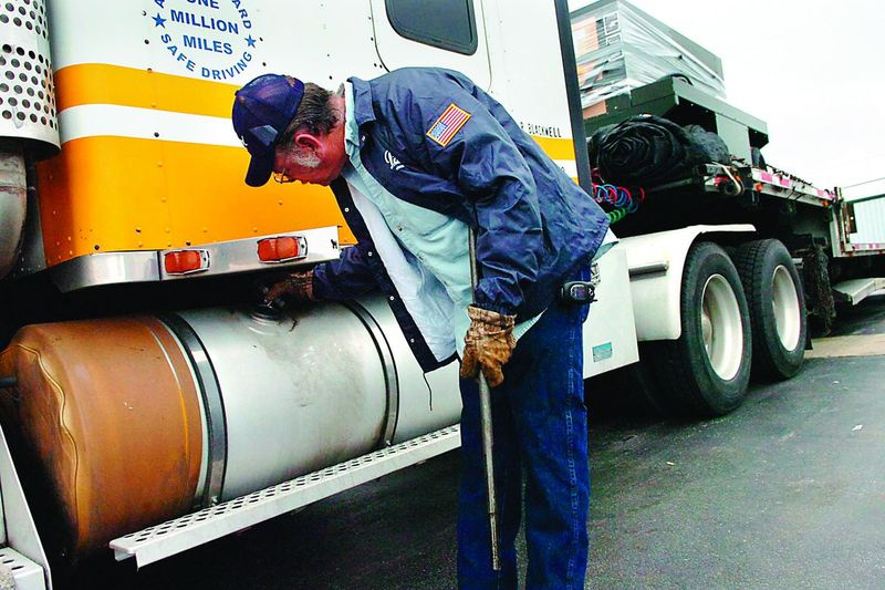 En förare kontrollerar gasnivån i en av två 150-liters tankar på sin diesel semi-truck på det här fotot från 2008.