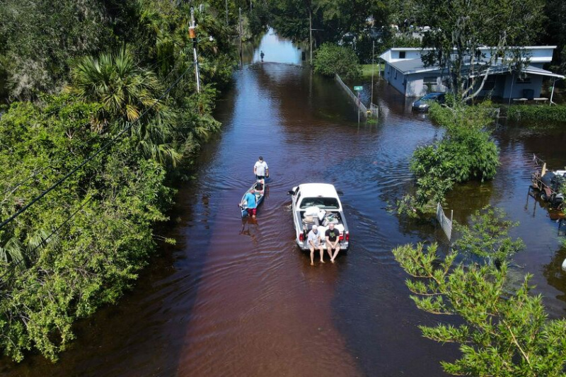   In dieser Luftaufnahme zieht ein Mann am 30. September 2022 ein Kanu durch eine überflutete Straße in seiner Nachbarschaft in New Smyrna Beach, Florida, nachdem der Hurrikan Ian das Gebiet getroffen hatte.