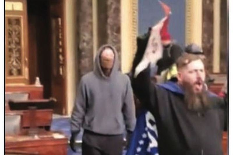 Federala myndigheter säger att detta foto föreställer Thomas B. Adams Jr. håller en Trumpflagga på golvet i den amerikanska senaten den 6 januari 2021.