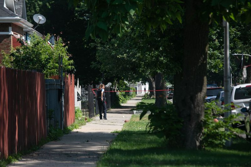 Полицајац уклања траку са места злочина где је 4. јула убијен 31-годишњи мушкарац док је седео на возачком месту у блоку 6400 Соутх Хоине Авенуе у Енглевооду. Укупно 875 људи је умрло од насиља из ватреног оружја. Округ Кук током целе године.