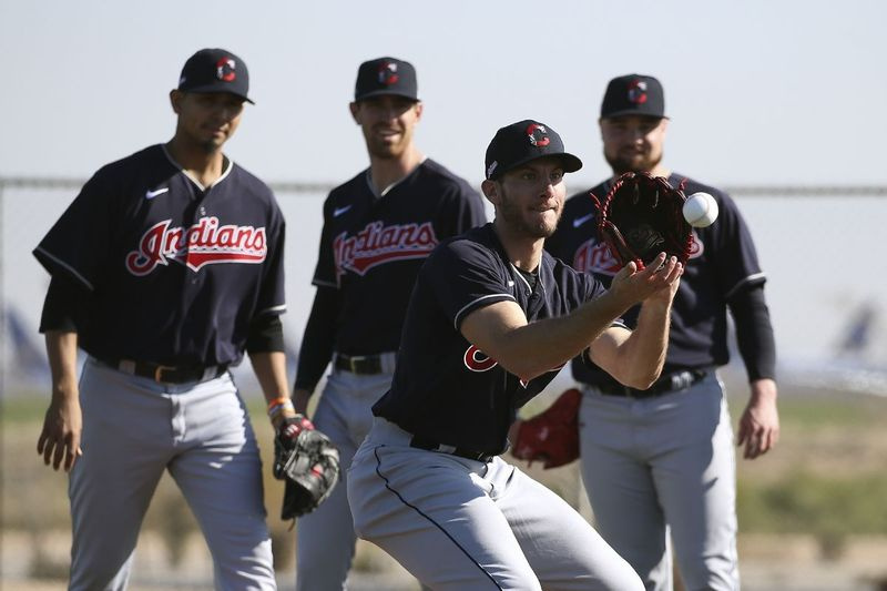 Den indiska pitchern Kyle Dowdy, främre, fält en boll när kastarna Carlos Carrasco, vänster, Shane Bieber, mitten, och Logan Allen, höger, tittar på under vårträningen.
