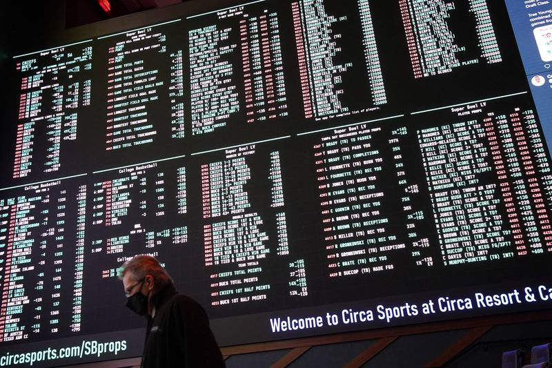 2月にラスベガスで開催されたCircaリゾートとカジノスポーツブックのモニターに、NFLフットボールのスーパーボウル55のベッティングオッズが表示されているときに、男性が通りかかった。