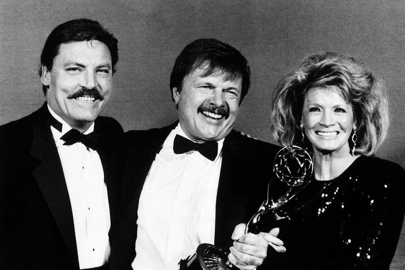 John Karlen (ao centro) posa com as apresentadoras Stacy Keach e Angie Dickinson depois de ganhar um Emmy de melhor ator coadjuvante em 1986.