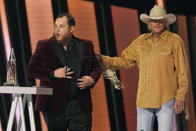 Luke Combs (vľavo) preberá cenu za zabávača roka, keď sa moderátor Alan Jackson pozerá na 55. výročné udeľovanie cien CMA v stredu večer v Bridgestone Arena v Nashville, Tennessee.