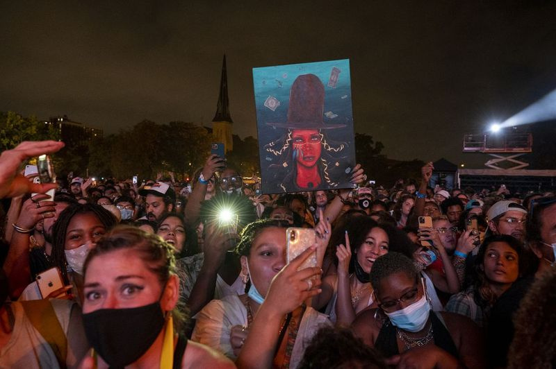 2021年9月12日日曜日にユニオンパークで開催されたピッチフォーク音楽祭で歌手が舞台に立っている間、ファンがエリカバドゥの絵を掲げています。