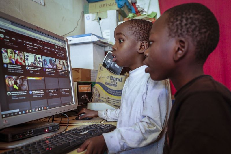 Zwei Jungen benutzen einen Computer in einem Internetcafé im einkommensschwachen Kibera-Viertel von Nairobi, Kenia.