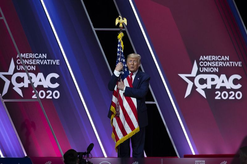 Na tym zdjęciu z 29 lutego 2020 r. Prezydent Donald Trump ściska i całuje amerykańską flagę po przemówieniu na Konferencji Konserwatywnej Działań Politycznych, CPAC 2020, w National Harbor w Oxon Hill.