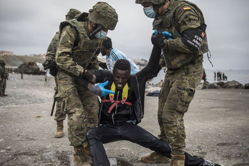 Un bărbat este reținut de militari ai armatei spaniole la granița dintre Maroc și Spania, la enclava spaniolă Ceuta, marți, 18 mai 2021. Ceuta, un oraș spaniol de 85.000 de locuitori din nordul Africii, se confruntă cu o criză umanitară după mii de oameni. dintre marocani au profitat de controlul relaxat la frontieră în țara lor pentru a înota sau a vâsli în bărci gonflabile în pământ european.