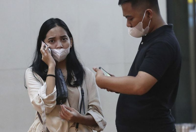 Anhöriga till passagerare använder sina mobiltelefoner på ett kriscenter som inrättats efter en rapport om att ett Sriwijaya Air-passagerarjetplan har tappat kontakten med flygledare kort efter starten, på den internationella flygplatsen Soekarno-Hatta i Tangerang, Indonesien på lördagen.
