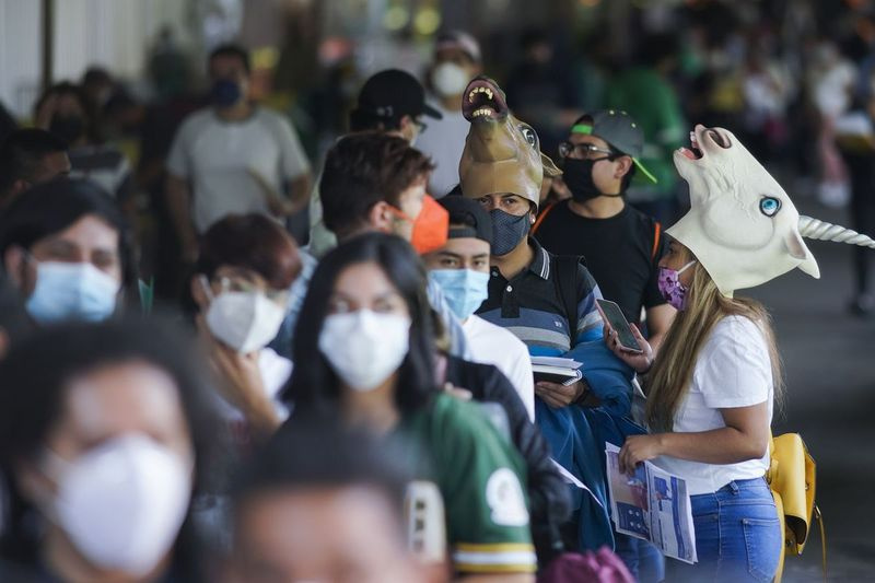 Unga människor, vissa bär masker, väntar på covid-19-skott under en vaccinationskampanj för personer mellan 18 och 29 år i Mexico City. Huvudstadens södra stadsdel Xochimilco uppmuntrar unga invånare att klä ut sig i kostymer och tävla om priser om de kommer för sin första covid-19-vaccindos.